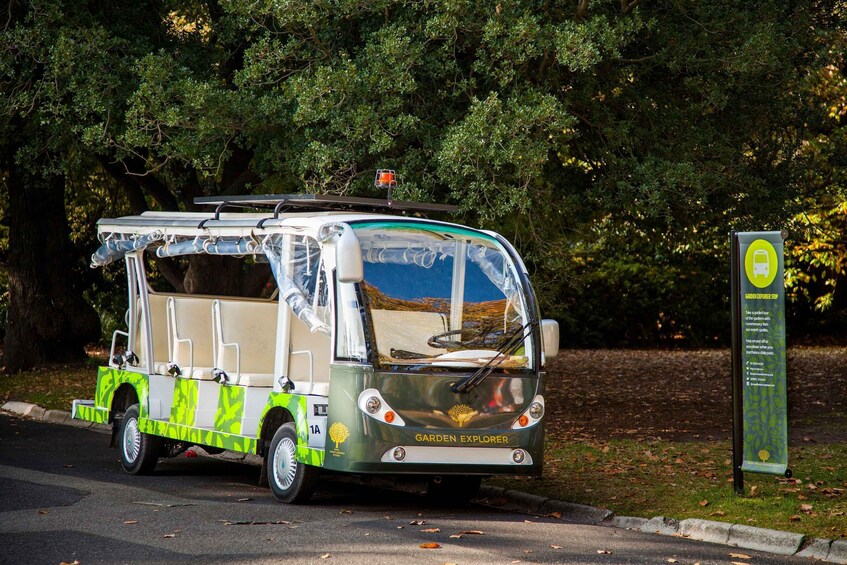 A green and white vehicle with a canopy, labeled "Garden Explorer," parked on a road with trees in the background. 3