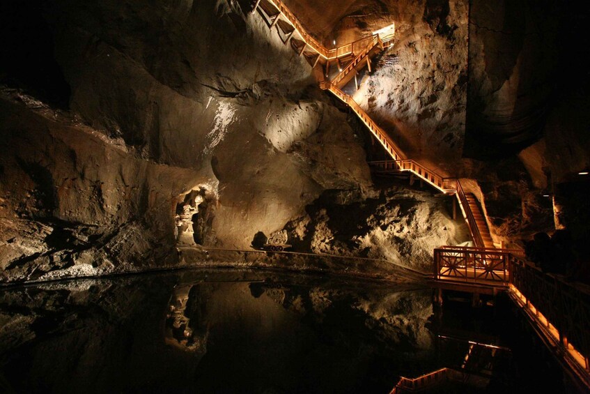 A cave with wooden walkways and a reflective water pool. 2