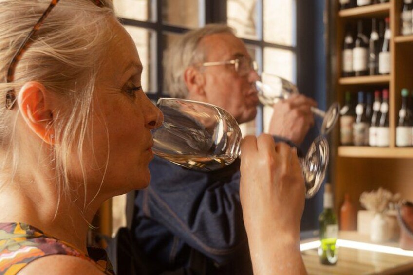 Zwei Personen verkosten Wein in einem Raum mit Weinflaschenregalen. 3