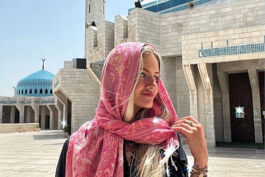 Una persona con un pañuelo rosa frente a un edificio con cúpula azul y ventanas arqueadas. 2