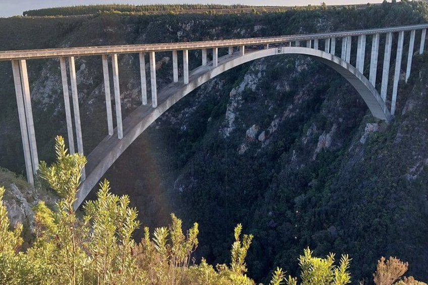 A large arched bridge spanning a deep gorge with steep cliffs on either side. 2