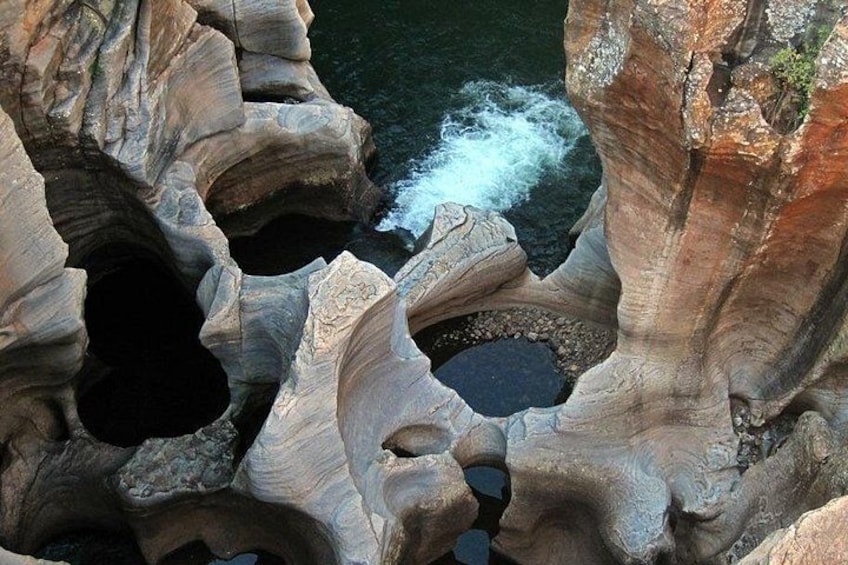 A rock formation with a water stream flowing through a natural cave. 3