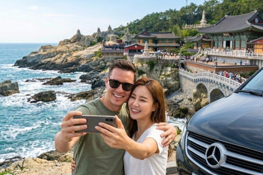 A couple taking a selfie by the sea with traditional architecture in the background. 1