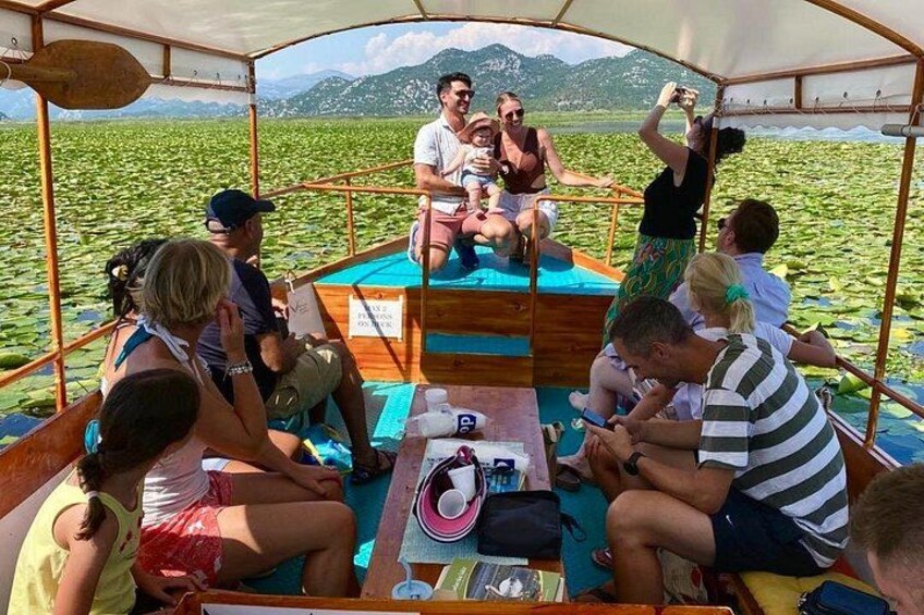 A group of people on a boat surrounded by water with greenery and mountains in the background. 2