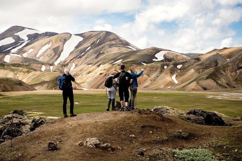 A group of hikers on a mountain trail with snow patches and a clear sky. 5