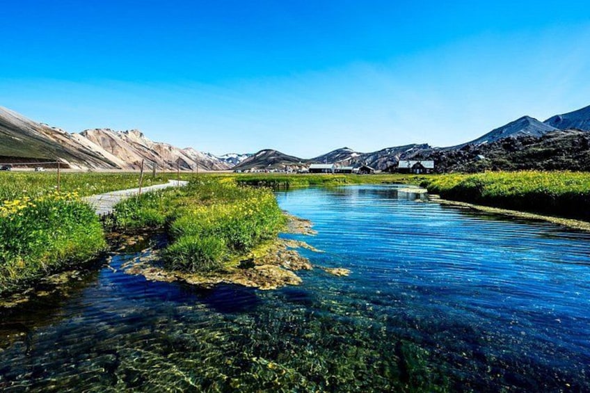 A clear river with surrounding greenery and distant mountains. 4