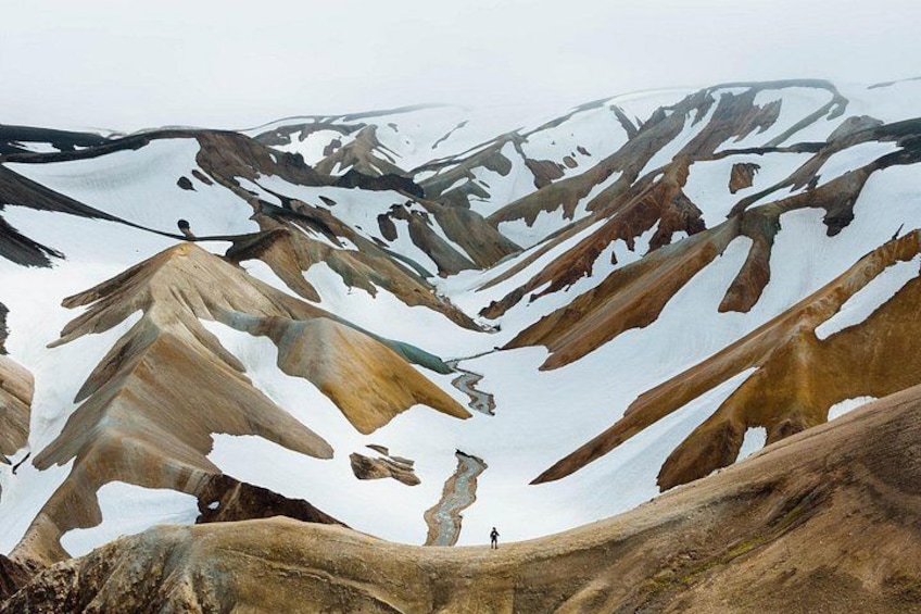 A mountainous landscape with snow-covered peaks and a person standing on a ridge. 3