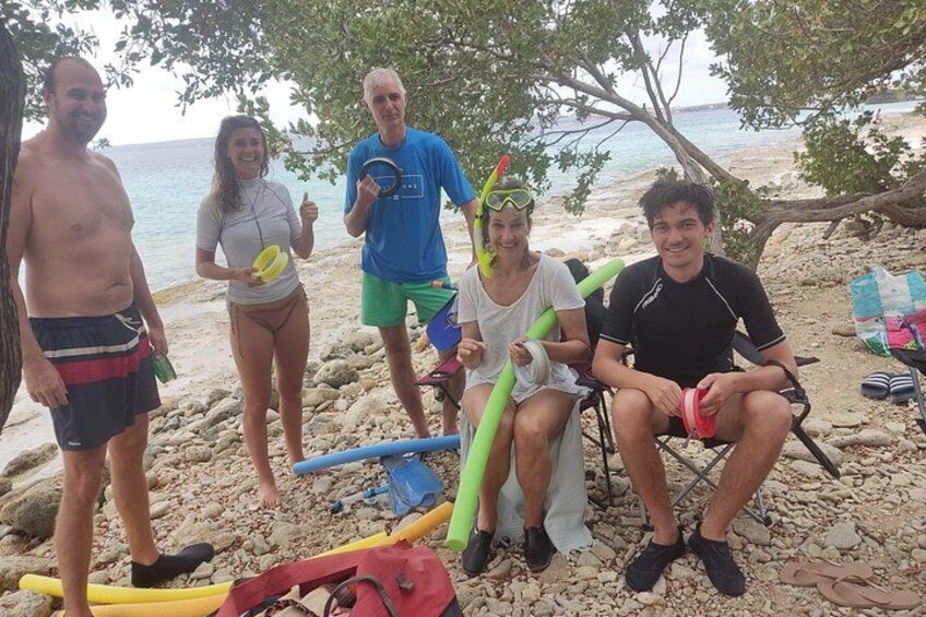 A group of people on a rocky beach with surfboards and a beach chair. 3