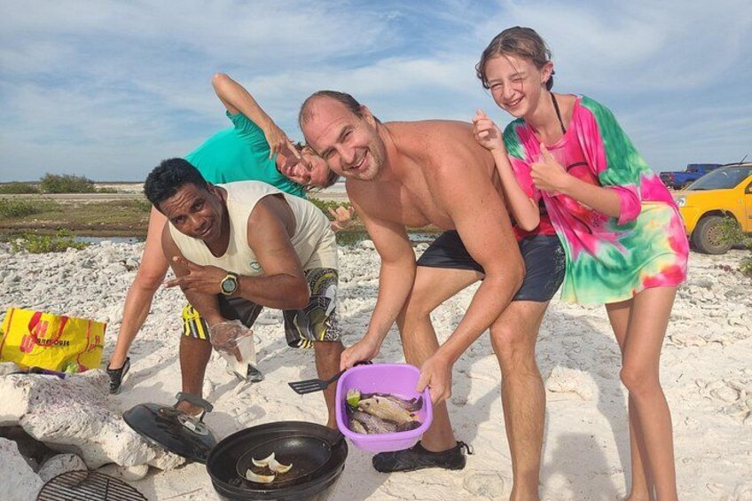 People on a sandy beach, a grill, and a yellow car in the background. 1