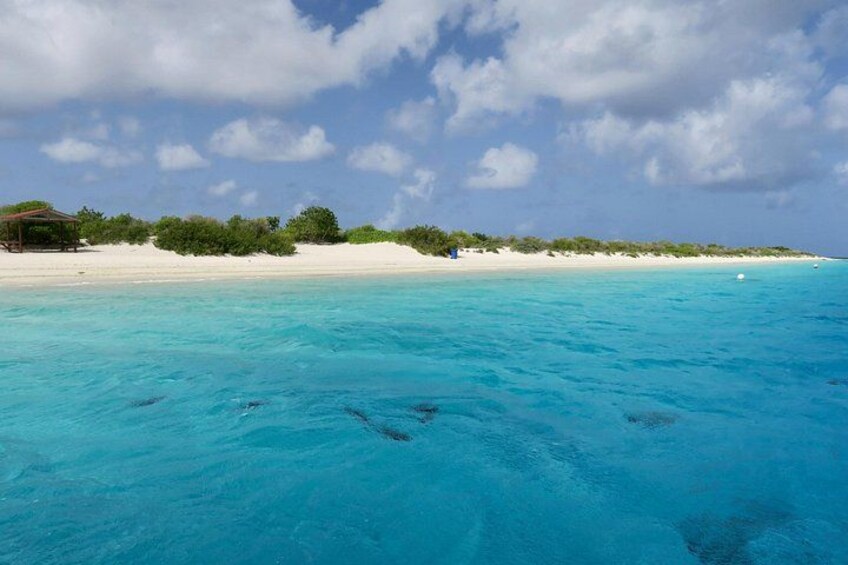 Una playa con agua turquesa cristalina, arena blanca y una pequeña estructura a la izquierda. 4
