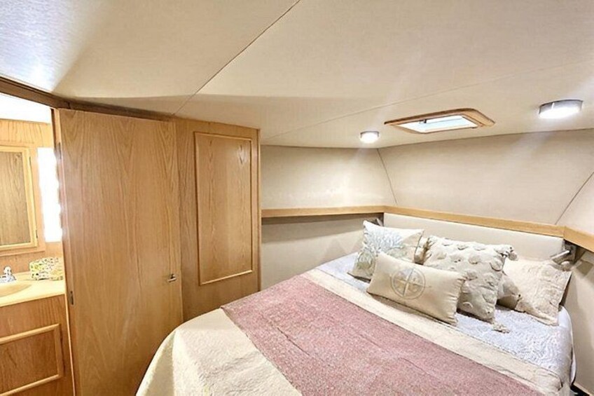 A bedroom with a bed, wooden wardrobe, and a small window. 3