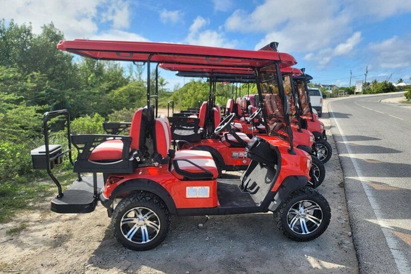 A red golf cart parked on a road with greenery in the background. 4