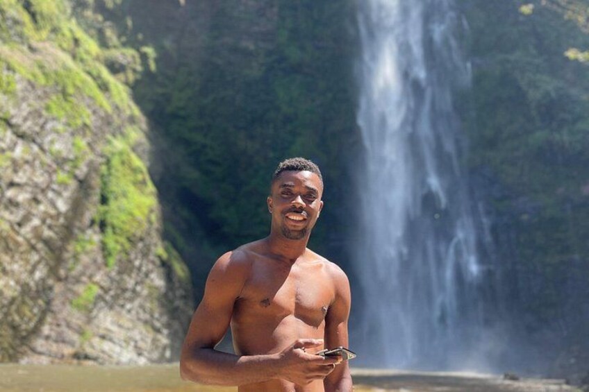 A person standing by a waterfall in a natural setting. 5