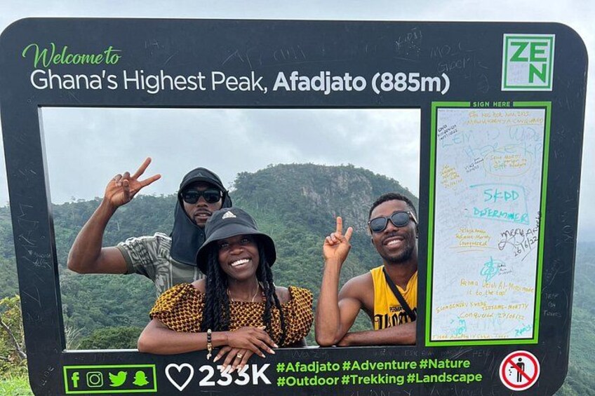 A sign welcoming visitors to Ghana's highest peak, Afadjato (885m), with a map and social media hashtags. 1