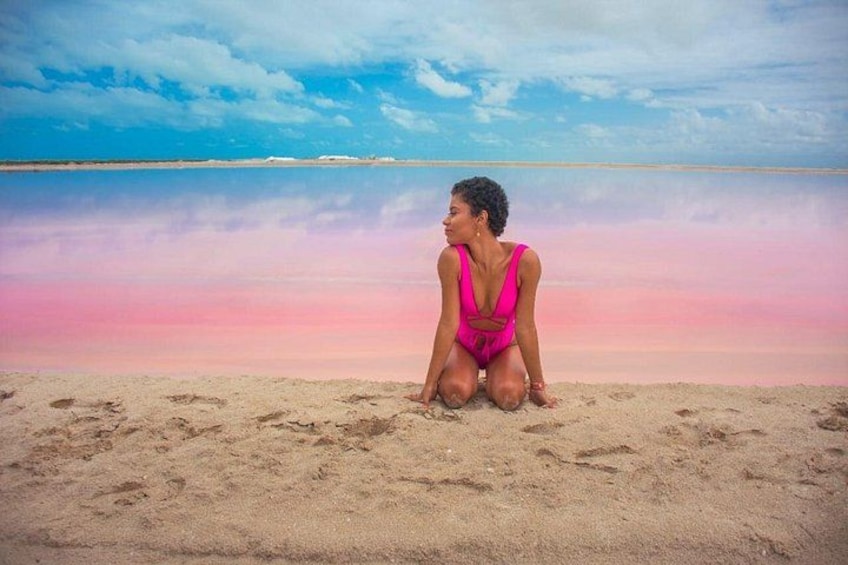 A person sitting on a sandy beach with a calm sea and a clear sky in the background. 1