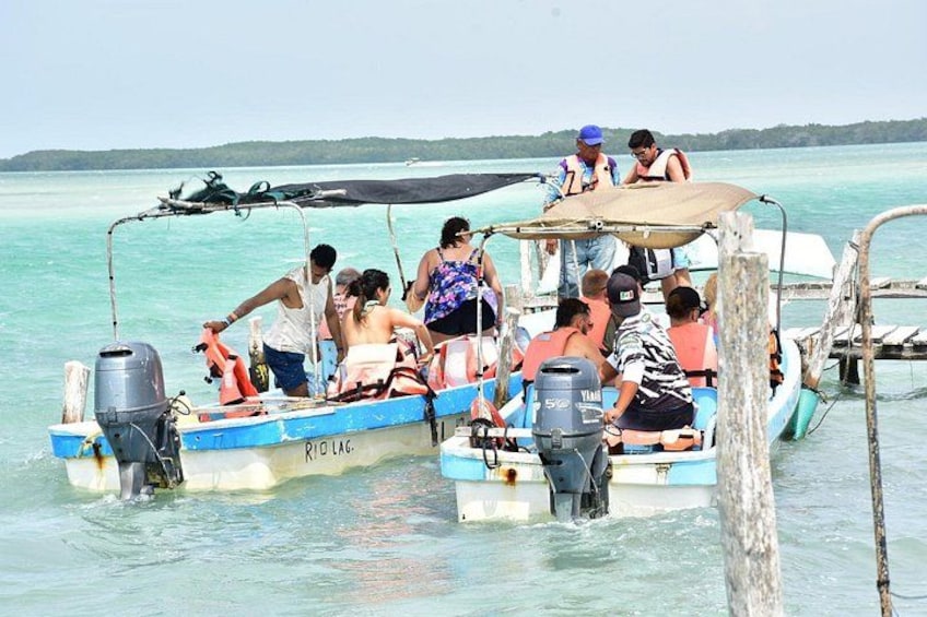 A group of people on a boat with a canopy, surrounded by calm waters and a distant shoreline. 2