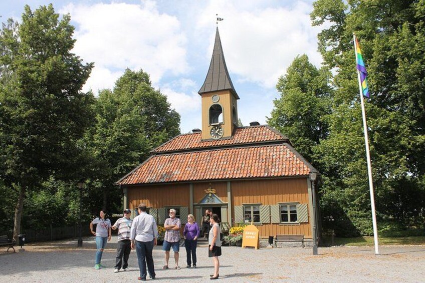 A church with a clock tower, surrounded by trees and a flagpole. 1