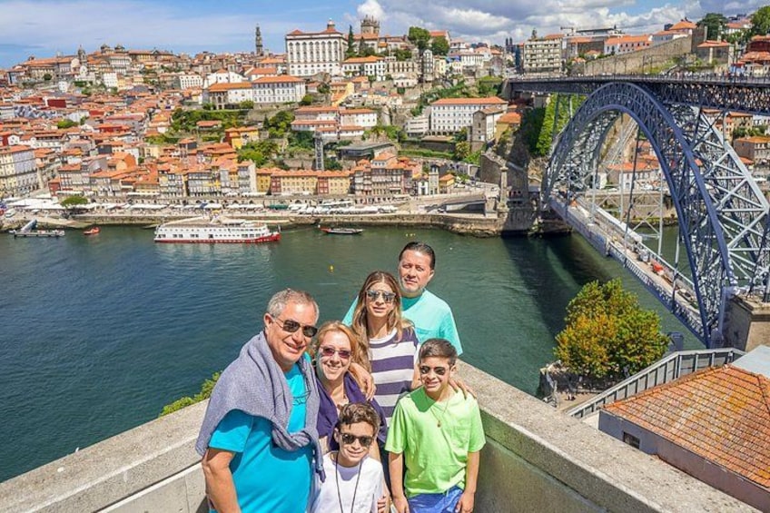 A group of people standing on a bridge with a cityscape and river in the background. 1