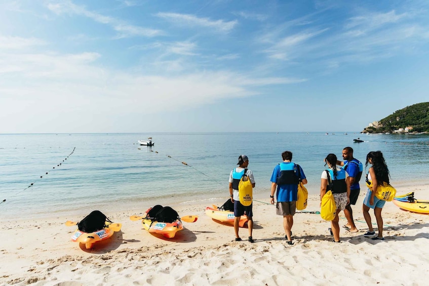 Un grupo de personas en una playa con kayaks y chalecos salvavidas. 1