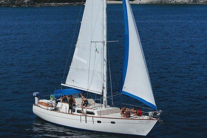 Un velero con velas blancas y detalles azules sobre aguas tranquilas. 2