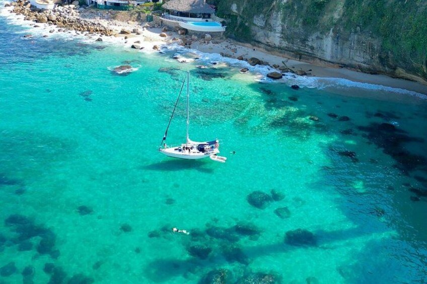 Un velero anclado cerca de una costa rocosa con agua turquesa cristalina. 1