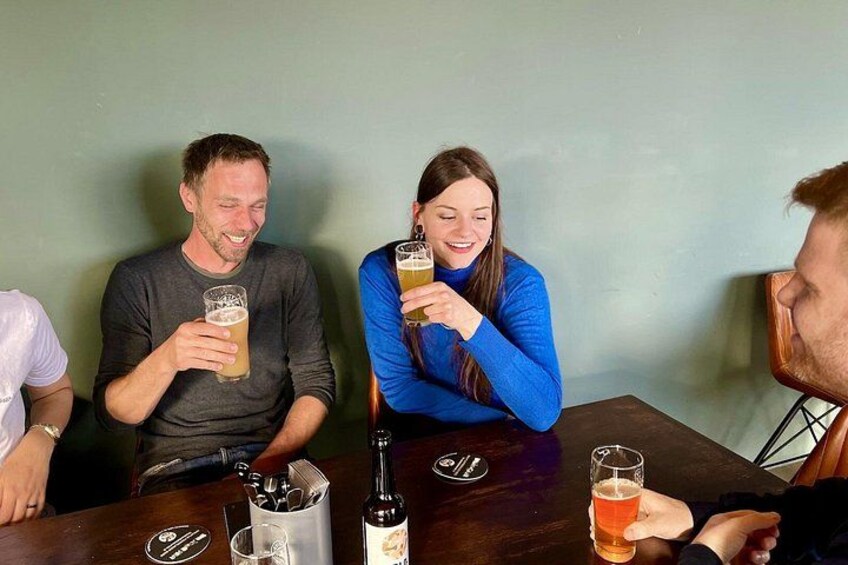 Drei Personen sitzen an einem Tisch mit Getränken, einer Flasche und einer Glas-Karaffe. 2