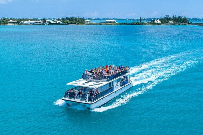 A boat with passengers on a turquoise sea, surrounded by clear skies and distant land. 3
