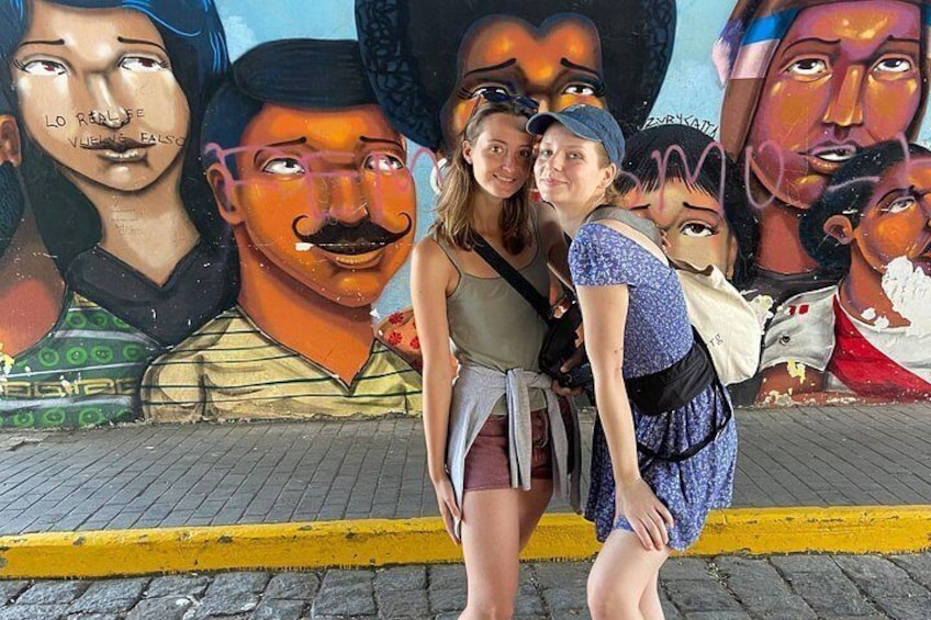 A mural with multiple faces and a yellow curb. 4
