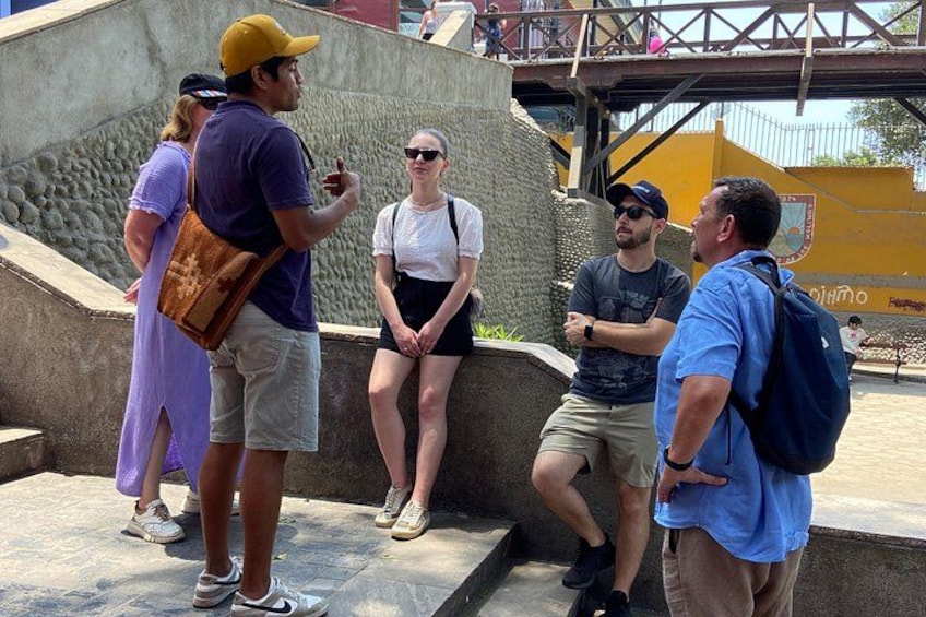 A group of people standing on steps near a concrete structure with a yellow wall in the background. 2