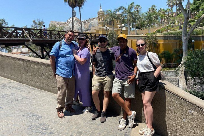 A group of people posing on a bridge with palm trees and a building in the background. 3