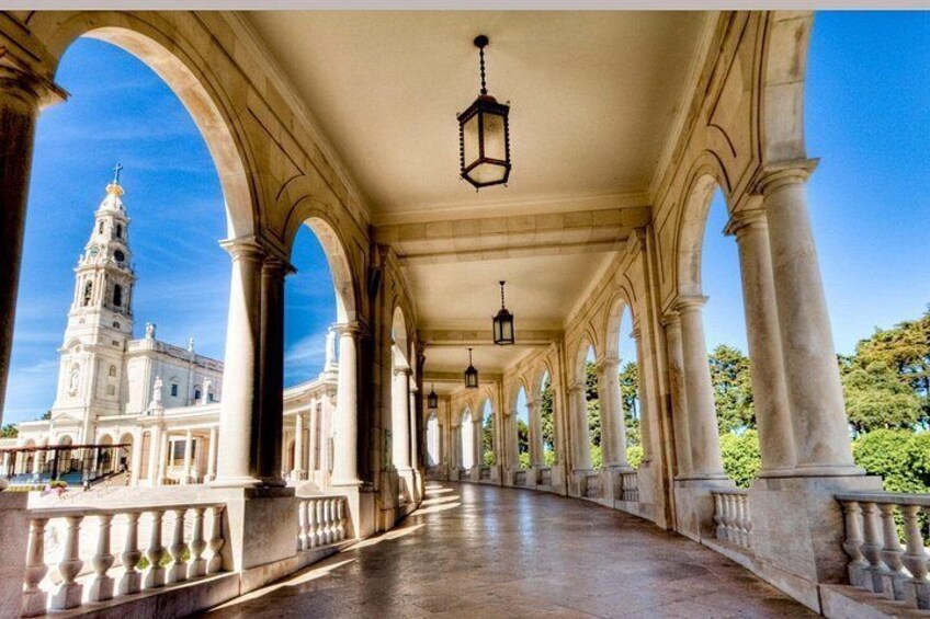 A covered walkway with arches, a building with a tower, and hanging lanterns. 5