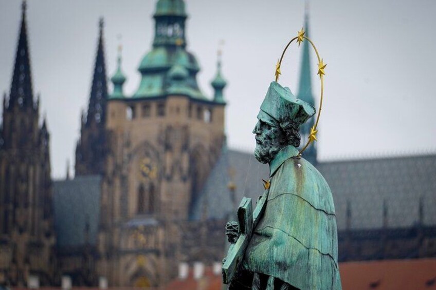 A statue of a historical figure with a crown and stars, in front of a large church with a green roof and spires. 3