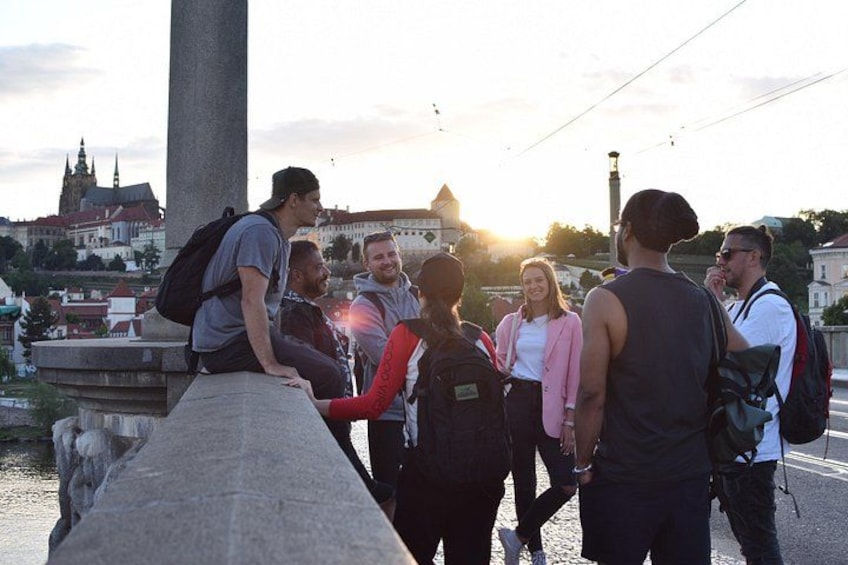 A group of people standing on a bridge with a historic building in the background. 4