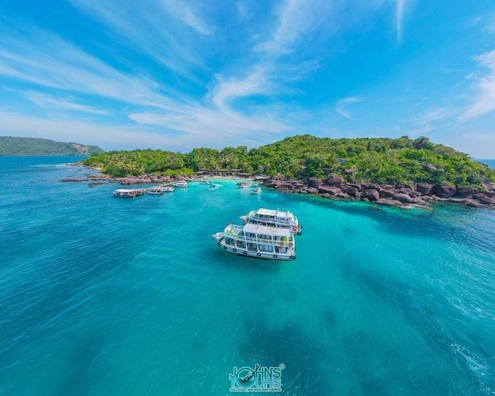 A boat on turquoise waters near a rocky island with lush greenery. 1