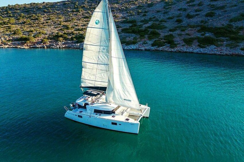 Un voilier sur une eau turquoise, avec une côte rocheuse en arrière-plan. 2