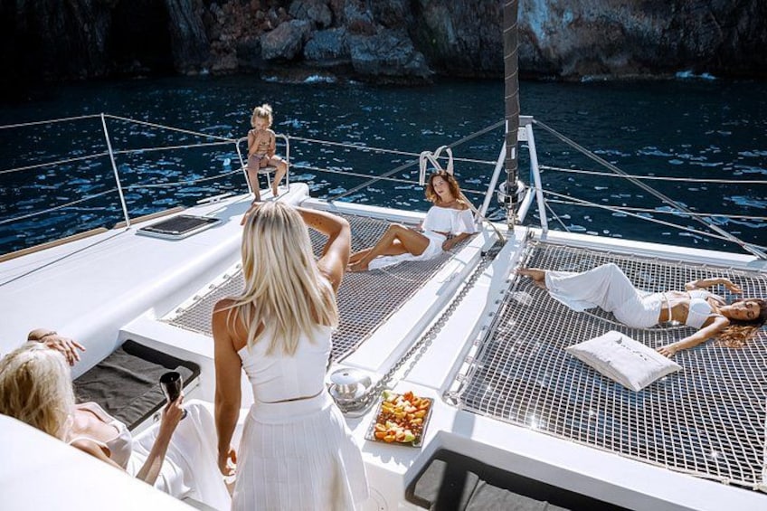 Eine Gruppe von Menschen auf einer Yacht vor einer felsigen Küstenlinie. 1