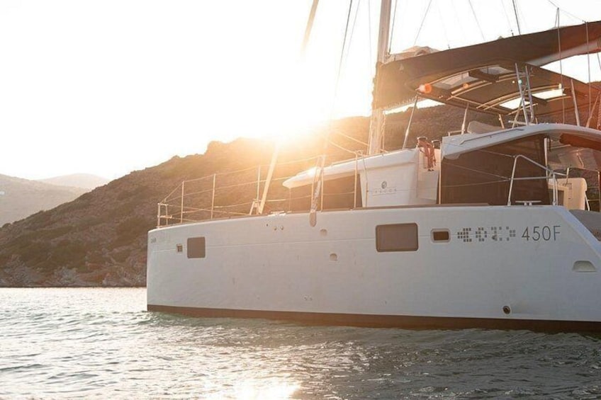 Eine weiße Yacht mit der Aufschrift 450F, vor Anker in der Nähe einer Brücke, mit Sonnenuntergang im Hintergrund. 2
