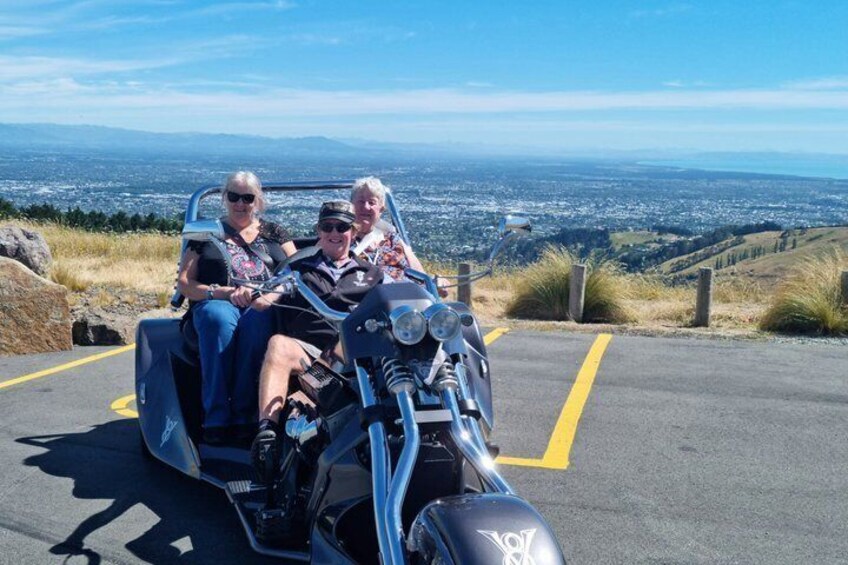 A group of people on a motorcycle tour, with a scenic view of a city and hills in the background. 4