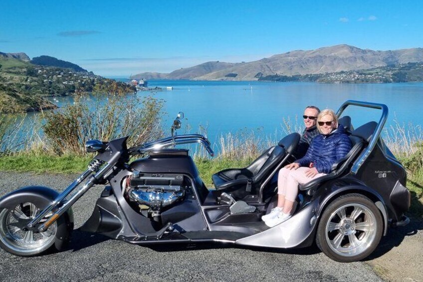 A black electric vehicle with a sidecar parked by a lake with mountains in the background. 3