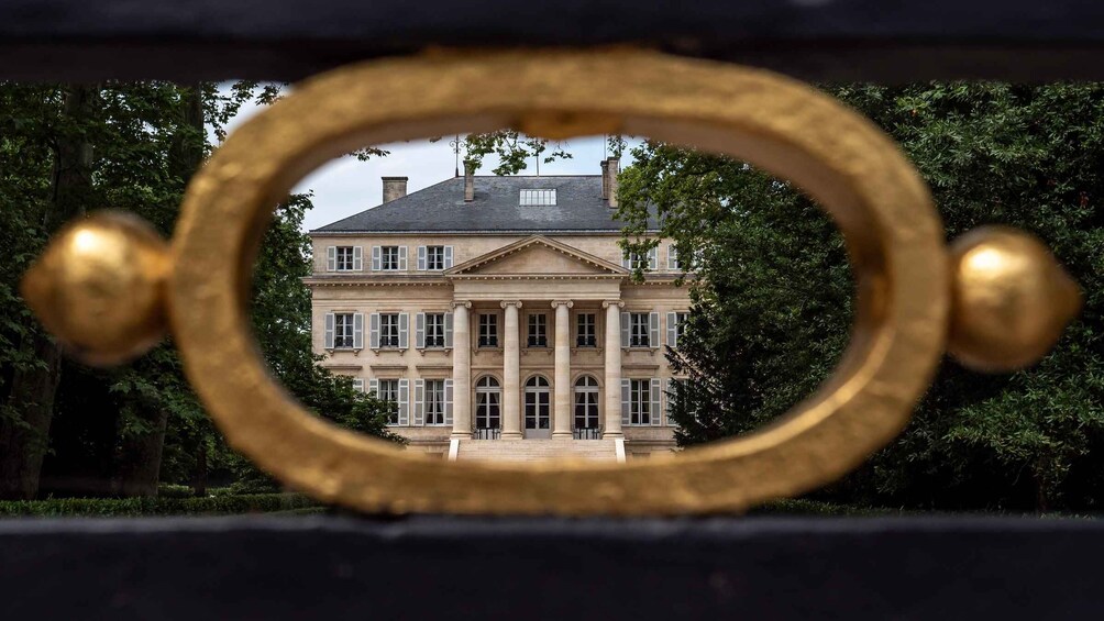 Un grand bâtiment de style classique, doté de colonnes et d’une façade symétrique, que l’on aperçoit à travers un miroir à cadre doré. 4