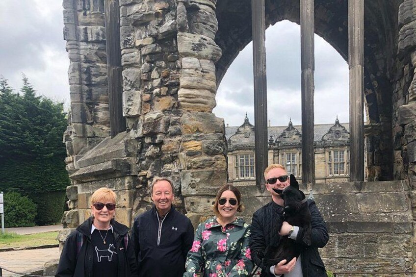 A stone archway with people standing in front of it. 3