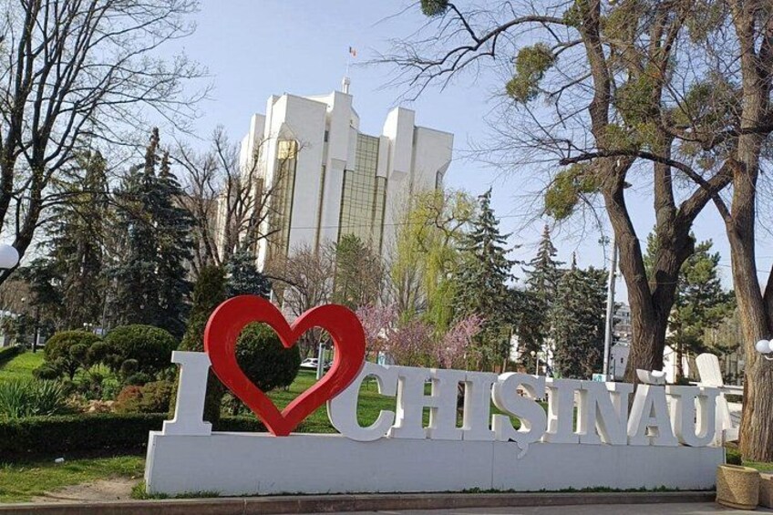 A sign with a heart-shaped cutout spelling 'CHISINAU' with a building in the background. 2