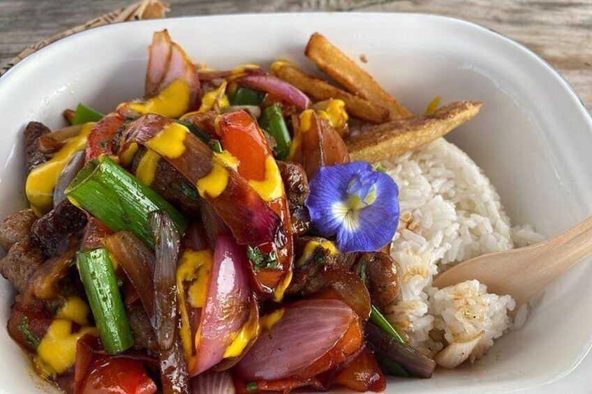 Un plato con verduras salteadas, carne, una guarnición de arroz y una flor decorativa. 4