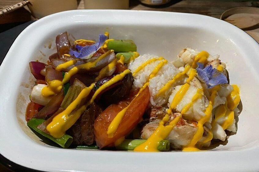 Un plato blanco con arroz, verduras y pescado, cubierto con salsa amarilla. 5