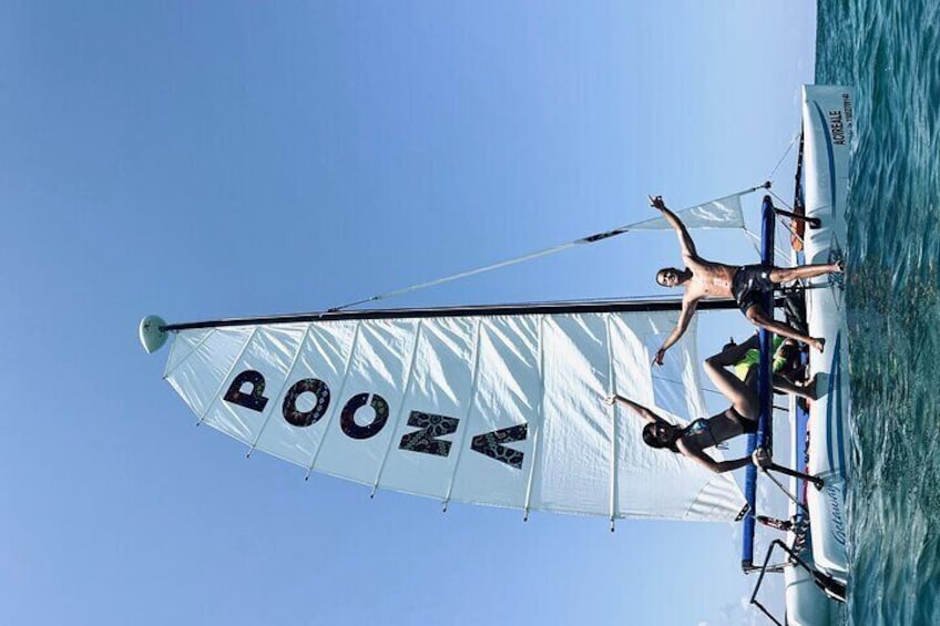 A sailboat with 'POOZA' written on its sail, two people on board, and calm water. 5
