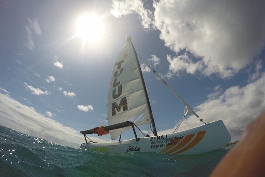 A sailboat named 'ETNA' on the water with a clear sky and sun. 1