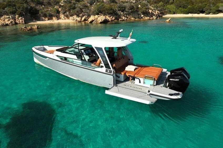 A motorboat with a cabin and outboard motor, floating on clear turquoise water. 1