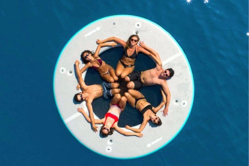 A circular floating platform with people lying on it in a pool. 5