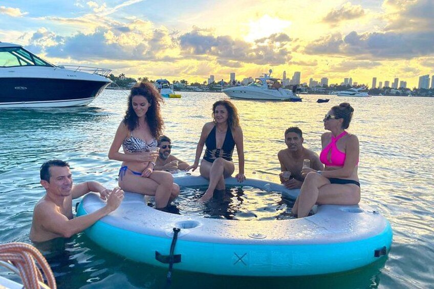A group of people on a floating platform in a body of water with boats in the background. 4