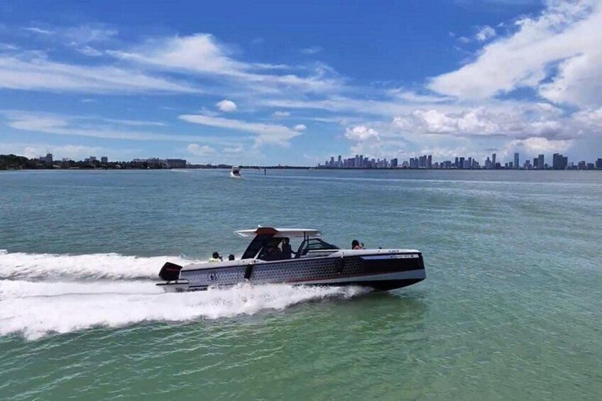 A speedboat on a body of water with a city skyline in the background. 2
